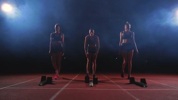 Giovane atleta corridore donna con smartwatch pronta a correre sulla linea di partenza della pista — Video Stock