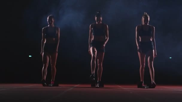 Ženské běžců v atletice sledovat, schoulil se na startovací bloky před závodem. V pomalém pohybu. — Stock video