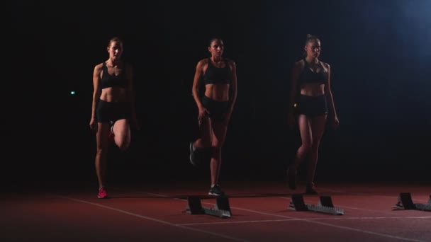 Corredores do sexo feminino no atletismo rastreiam agachamento nos blocos iniciais antes de uma corrida. Em câmara lenta . — Vídeo de Stock