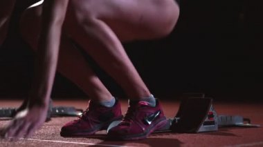 Atletizm, kadın koşucu bir yarıştan önce başlayan blok, çömelme izlemek. Ağır çekimde.