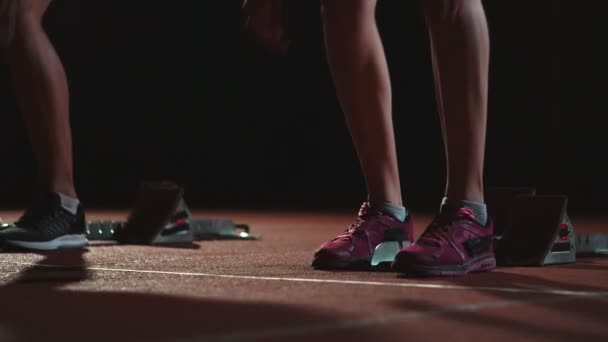 Corredores do sexo feminino no atletismo rastreiam agachamento nos blocos iniciais antes de uma corrida. Em câmara lenta . — Vídeo de Stock