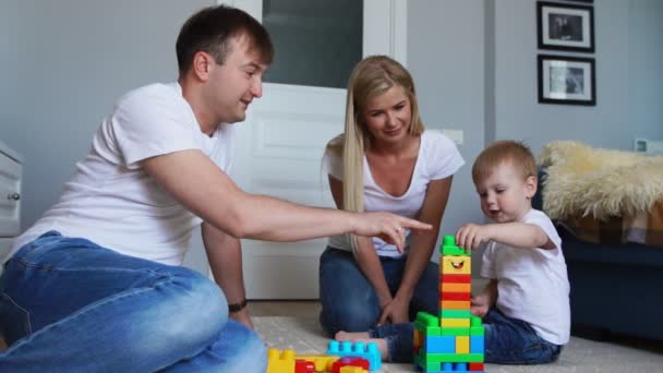 Ευτυχισμένη οικογένεια μπαμπάς μαμά και το μωρό 2 ετών να παίζουν lego σε φωτεινό σαλόνι τους. Αργή κίνηση γυρίσματα ευτυχισμένη οικογένεια — Αρχείο Βίντεο
