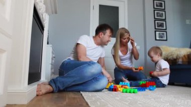 Mutlu aile baba anne ve bebek 2 yıl onların parlak oturma odasında lego oynarken. Ağır çekim mutlu aile çekim