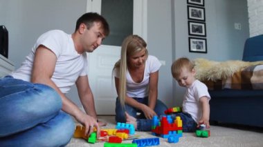 Mutlu aile baba anne ve bebek 2 yıl onların parlak oturma odasında lego oynarken. Ağır çekim mutlu aile çekim