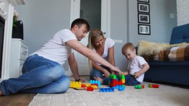 Mutlu aile baba anne ve bebek 2 yıl onların parlak oturma odasında lego oynarken. Ağır çekim mutlu aile çekim