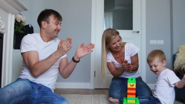 Papa en Mama klappen in hun handen, en zich verheugen op het succes van de zoontje, ranselen hem voor een golf van taak van Lego. — Stockvideo