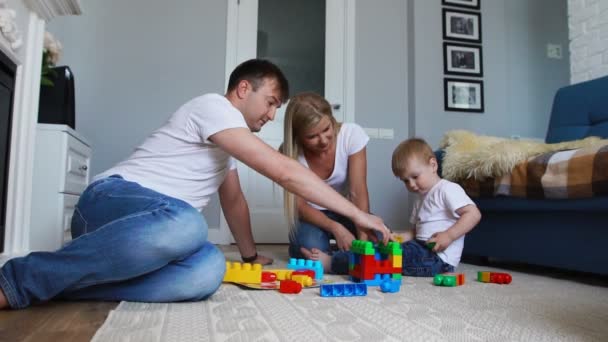 Gelukkig gezin vader moeder en baby 2 jaar lego spelen in hun lichte woonkamer. Slow-motion-video schieten gelukkige familie — Stockvideo