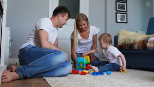 Gelukkig gezin vader moeder en baby 2 jaar lego spelen in hun lichte woonkamer. Slow-motion-video schieten gelukkige familie — Stockvideo