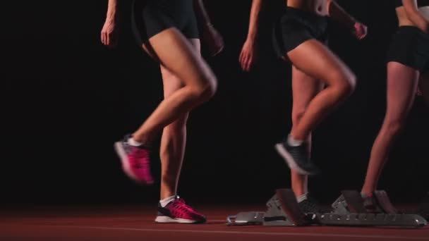 Три дівчини в чорному одязі на стартових майданчиках, щоб почати гонку в змаганнях у світлі ліхтарів . — стокове відео