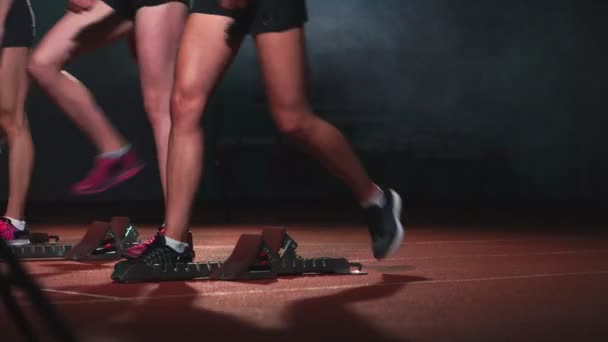 Trois sportives vêtues de noir de l'athlète la nuit sur le tapis roulant partiront pour la course à la distance de sprint de la position assise . — Video