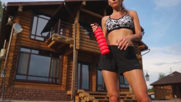 Brunetka, zmęczony po treningu cardio w podwórzu domu pije wodę z butelki — Wideo stockowe