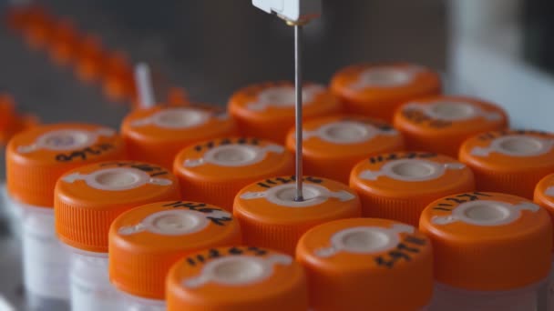 Close-up no laboratório médico, o robô perfura um frasco de líquido com uma agulha e o derrama em um tubo para análise posterior pelo médico — Vídeo de Stock