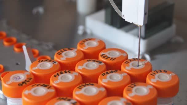 Gros plan dans le laboratoire médical, le robot perce un pot de liquide avec une aiguille et le verse dans un tube pour une analyse plus approfondie par le médecin 