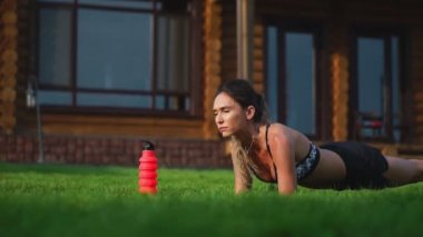 güzel esmer arka planda büyük bir köşkün fitness nişanlı ve açık havada eğitim basın için tahta egzersiz gerçekleştirir