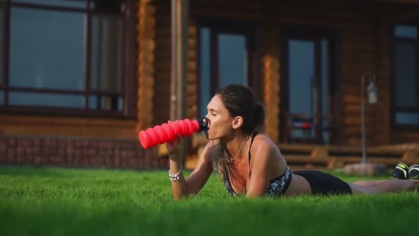 Подходит девочка, делающая упражнения на досках под открытым небом в парке теплым летним днем. Концепция выносливости и мотивации — стоковое видео