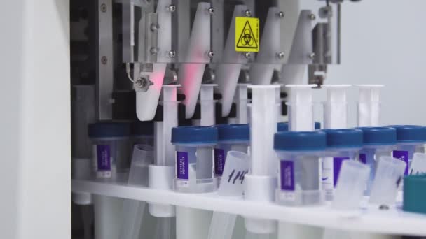 Close-up in the medical laboratory, the robot pierces a jar of liquid with a needle and pours it into a tube for further analysis by the doctor — Stock Video