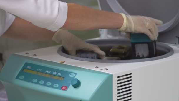 실험실에서 목욕 가운과 장갑에 여자 untwist 셀의 여분의 레이어를 분리 하는 원심 분리기에서 시험관에서 인간의 세포 샘플을 설정 합니다. 뚜껑을 열고 꺼내서 테스트 튜브 — 비디오