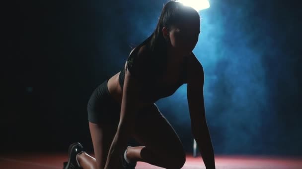 Стройная юная спортсменка в состоянии начать бегать в подушечках на треке в замедленной съемке — стоковое видео