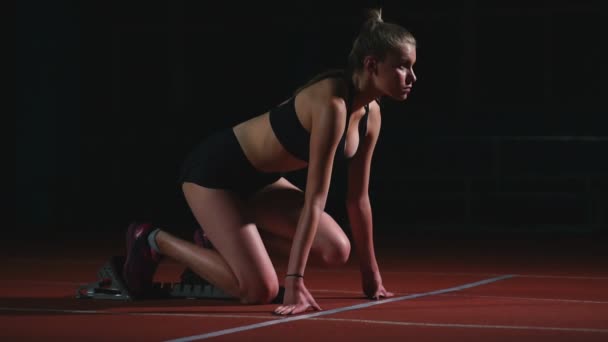 Professionele vrouw atleet op een donkere achtergrond te lopen van de sprint van Jogging schoenen in sneakers op het spoor van het stadion op een donkere achtergrond — Stockvideo