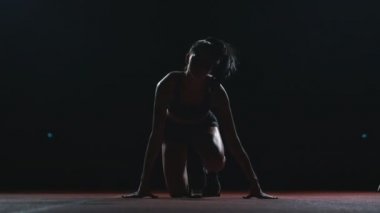 Kadın atlet karanlık bir arka plan üzerinde çapraz ülke pad sprint koşu bandı karanlık bir arka plan üzerinde çalıştırmak için