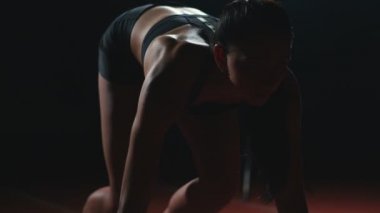 Koşu ayakkabıları sprint spor ayakkabı içinde stadyumun parça koyu arka plan üzerinde çalıştırmak için profesyonel kadın atlet karanlık bir arka plan üzerinde