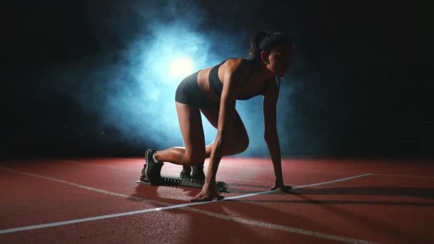 职业女子运动员在黑暗的背景下跑短跑运动鞋在体育场的轨道上在黑暗的背景 — 图库视频影像