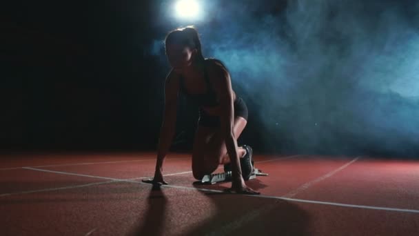 Atlet wanita dengan latar belakang gelap bersiap untuk berlari dari bantalan di atas treadmill dengan latar belakang gelap — Stok Video