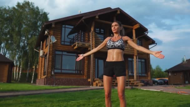 Mujer hermosa delgada en ropa deportiva en el fondo de la casa en el césped realiza saltos para el entrenamiento cardiovascular y la quema de grasa — Vídeo de stock