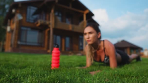 Belle brune sur le fond d'un grand manoir engagé dans la remise en forme et effectue des exercices de planche pour la presse, l'entraînement en plein air — Video