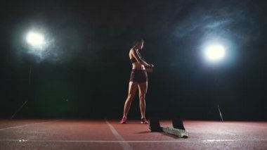 Koşu ayakkabıları sprint spor ayakkabı içinde stadyumun parça koyu arka plan üzerinde çalıştırmak için profesyonel kadın atlet koyu arka plan gotovtes üzerinde. Ortalama planı.