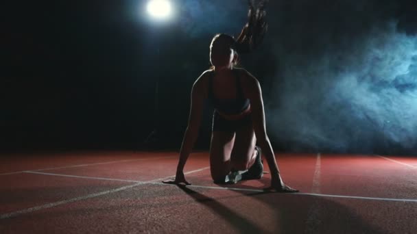 Kobieta lekkoatletka w czarne spodenki i koszulki w trampki są uruchomione klocki na torze kompleks sportowy i uruchomić w zwolnionym tempie — Wideo stockowe