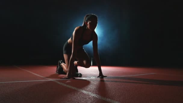 Slank jong meisje atleet is in staat om de begint te lopen in de pads op het spoor in slow motion — Stockvideo