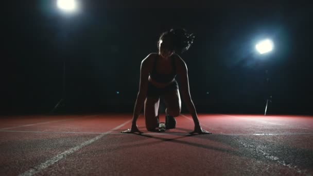 苗条的年轻女孩的运动员是在位置开始跑在轨道上在慢动作的垫 — 图库视频影像