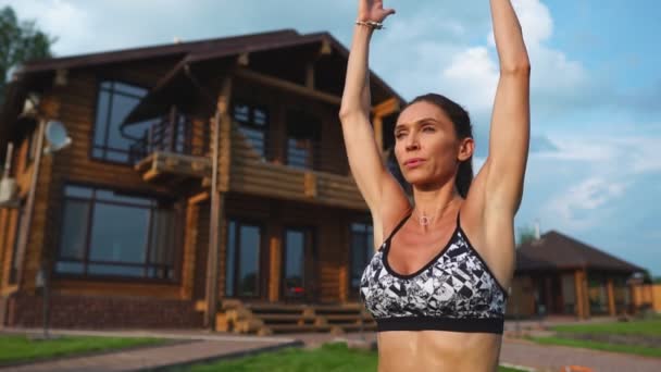 Mujer hermosa delgada en ropa deportiva en el fondo de la casa en el césped realiza saltos para el entrenamiento cardiovascular y la quema de grasa — Vídeo de stock