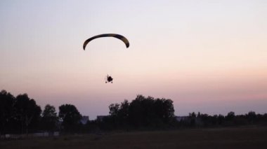 Bir yamaçparaşütü pilota günbatımı ve gece peyzaj üzerinde gökyüzünde uçar. arka plan