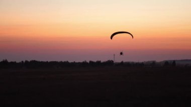 Günbatımından sonra paraşütçü pilot turuncu ile gökyüzünde uçar. arkaplan