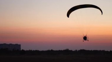 Yavaş yavaş uzak mesafe günbatımı güzel gökyüzü karşı içine hareketli kamera pilot bir paraglider üzerinde uçar.