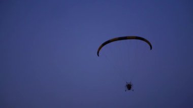 Yavaş yavaş uzak mavi gökyüzüne karşı mesafe içine hareketli kamera pilot bir paraglider üzerinde uçar