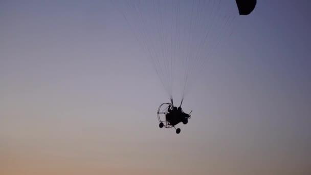 在滑翔伞上的飞行员从相机上飞过, 渐渐地朝着日落美丽的天空飞去。美丽的背景背景图片。自由的概念 — 图库视频影像