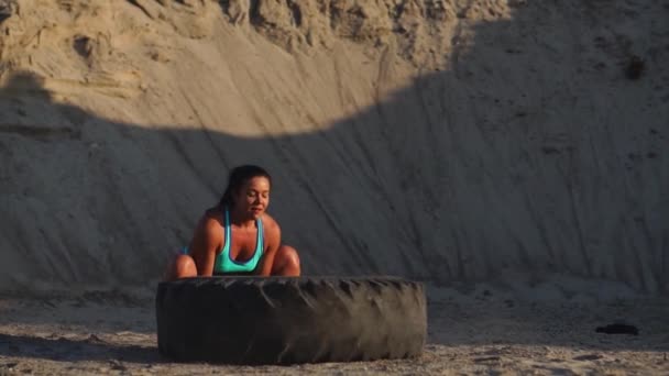 Uma rapariga de fato desportivo empurra um pneu. Treino de rua . — Vídeo de Stock