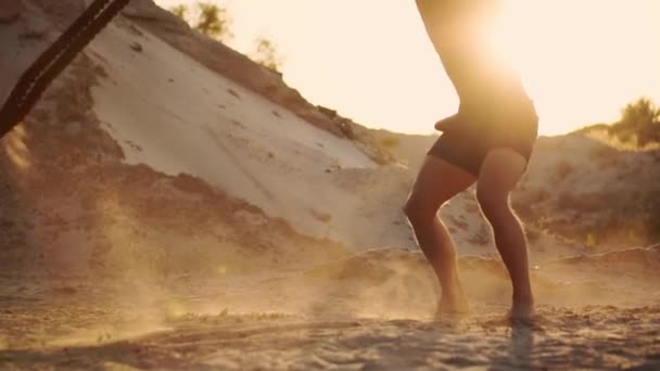 Αρσενικό αθλητής κάνει push-Ups στην παραλία και χτυπώντας το σκοινί με το έδαφος, εγκύκλιος επιμόρφωσης στον ήλιο πάνω σε μια αμμώδη παραλία, τη δηµιουργία σκόνης σε αργή κίνηση. — Αρχείο Βίντεο
