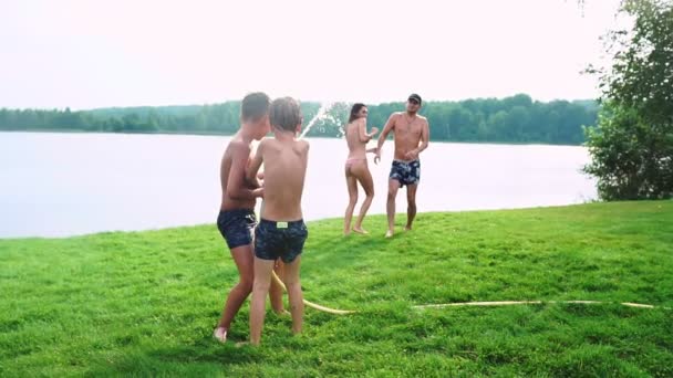 화창한 여름 날 잔디밭에 두 아이 함께 가족 물 놀고 웃 고 재미 있다. 행복 한 가족의 쾌활 한 분위기 — 비디오