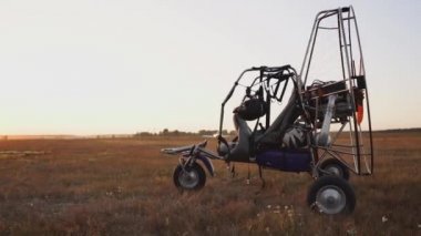 Günbatımı güneş ışınlarının havaalanında motorlu yamaçparaşütü duruyor. Arka planda, uçak çıkartıyor ve paraşütçü otur. Kamera yörünge hareket eder.