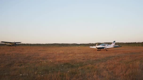 Op de luchthaven, het vliegtuig opstijgt en de paraglider is in het zonlicht zonsondergang — Stockvideo