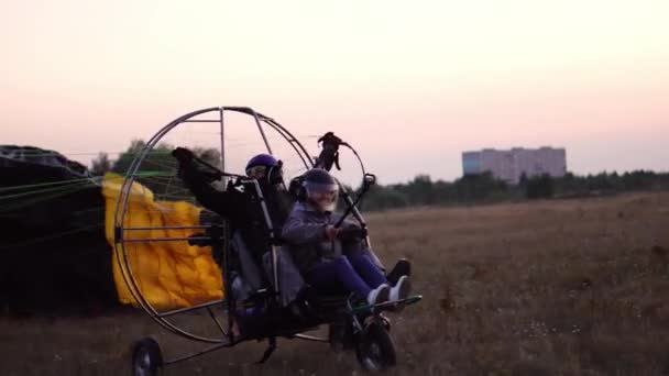 El parapente del motor despega con una chica y un hombre en el aeropuerto acelerando y despegando hacia el cielo en paracaídas — Vídeos de Stock