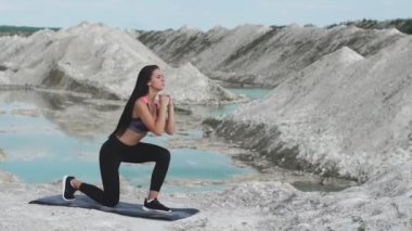 Siyah spor giyim trenler mavi su ile beyaz tebeşir kum ocağı karşı sportif esmer kız. Lunges her bacak için uyluk üzerinde
