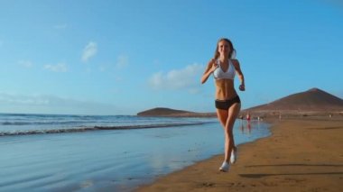 Etkin yaz tatili deniz kenarında güzel kumlu plaj boyunca, sağlıklı yaşam, çalışan güzel sportif kadının. ağır çekimde