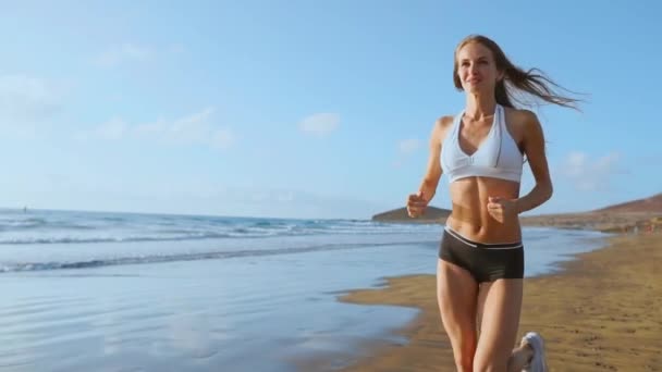 Mujer atleta silueta corriendo en playa corriendo olas estrellándose en la playa mañana fondo cámara lenta — Vídeo de stock