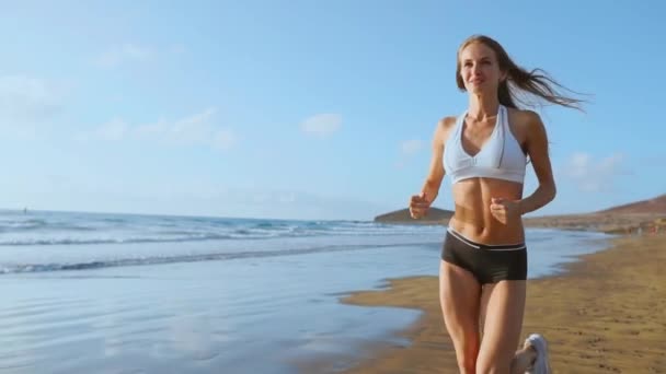 Mujer atleta silueta corriendo en playa corriendo olas estrellándose en la playa mañana fondo cámara lenta — Vídeos de Stock