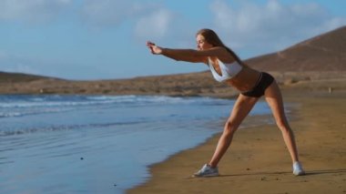 Kadın germe bacaklar ve ileri ayakta Bend Yoga streç yapmak hamstrings sahilde poz. Rahatlatıcı ve üzerinde spor ve yoga pratik fitness kadın.